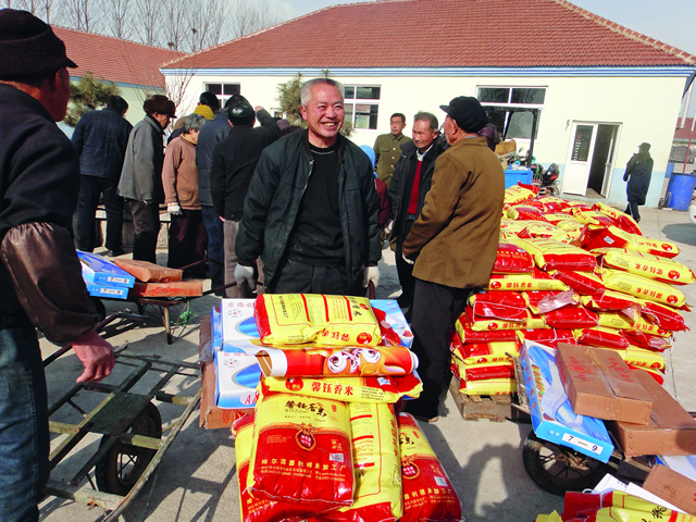 十几年前，日本侨眷丛滋岗在其出生地文登市葛家镇祝家泊子村投资4000多万元成立文登安新食品厂，不但解决了村民的就业问题，还每年为村集体增收20万元，村民增加收入300多万元。丛滋岗还规划投资建设了村委办公室、老年活动中心、卫生院、文化书院、健身广场、路面硬化绿化等。图为2011年1月春节前夕，丛滋岗为村里群众发放年货.jpg